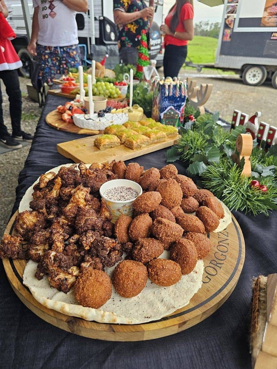 Christmas food spread on a table outdoors with people in the background. - The Habibiz Catering in Wingham NSW