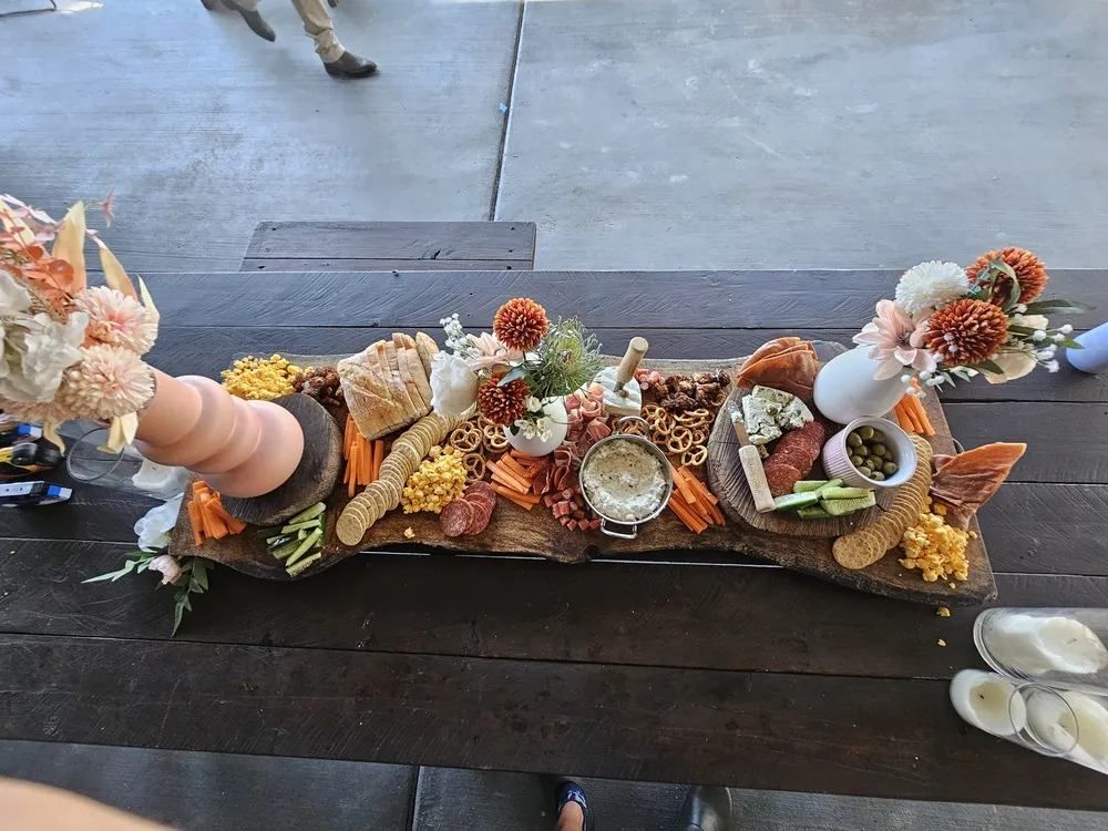 Charcuterie Board on A Wooden Table with A Floral Arrangement — The Habibiz Catering in Taree, NSW