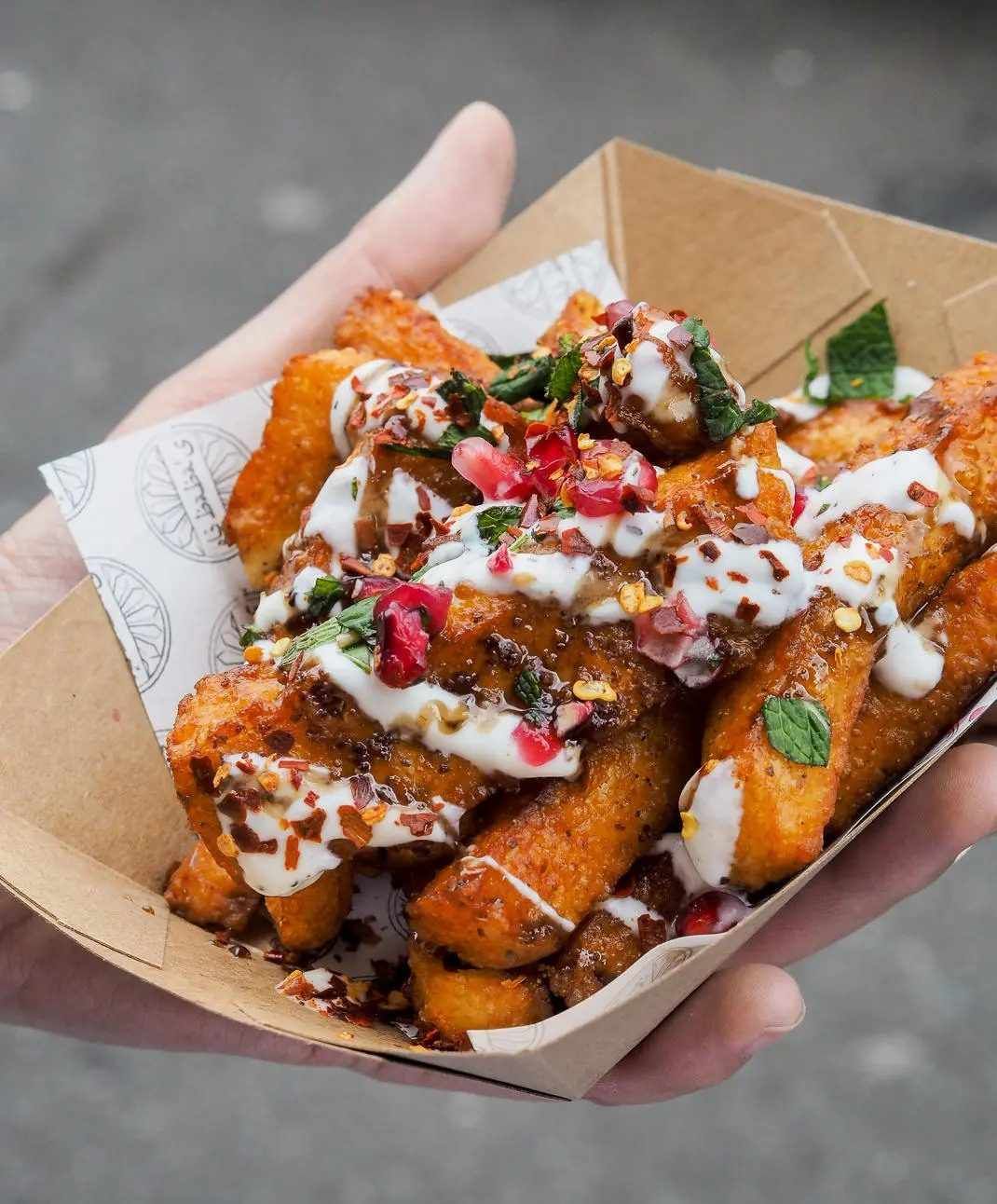 Hand Holding a Cardboard Tray of Fried Food — The Habibiz Catering In Wingham, NSW