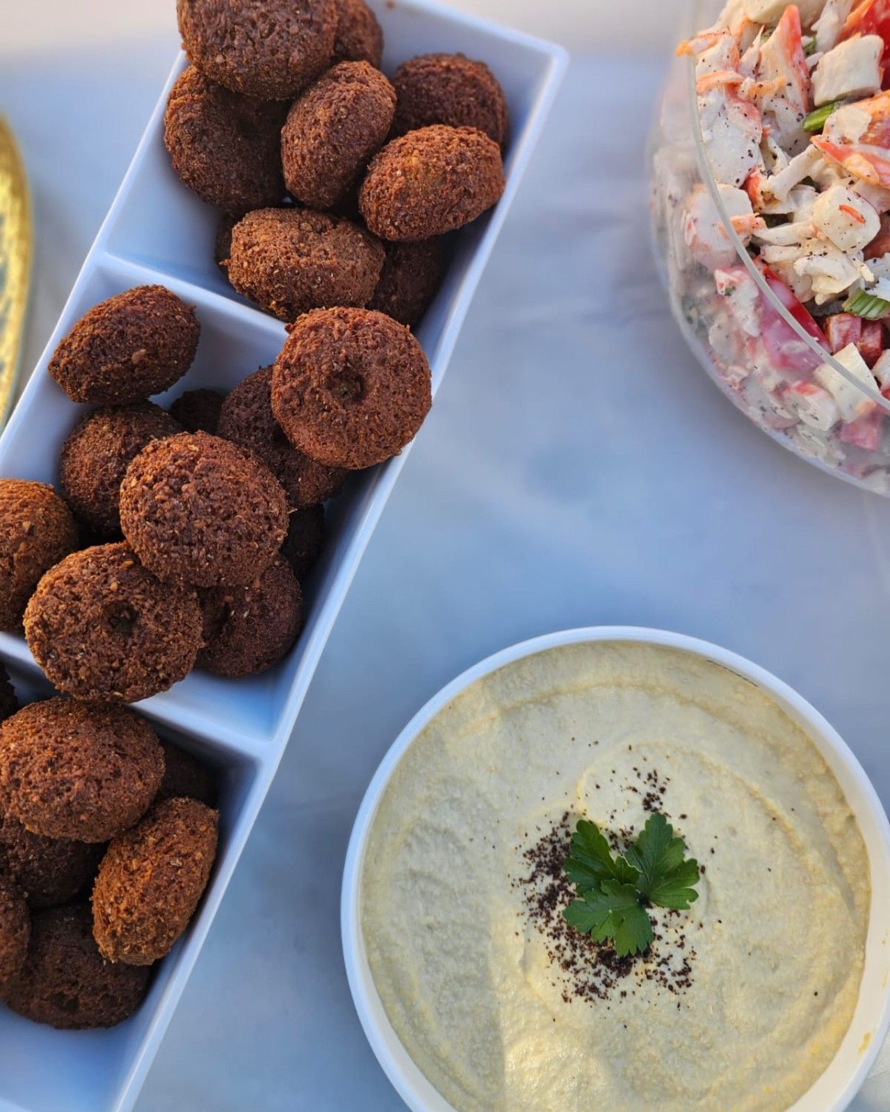 Falafel in a divided dish, hummus, and a salad on a white surface. - The Habibiz Catering in Wingham NSW