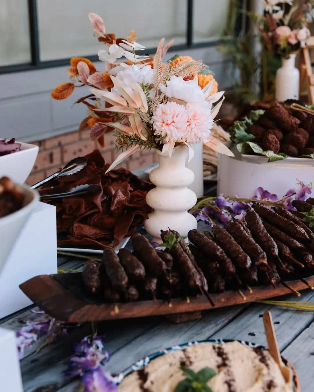 Buffet Table with A Floral Arrangement, Kebabs, Hummus, and Various Appetizers — The Habibiz Catering in Forster, NSW
