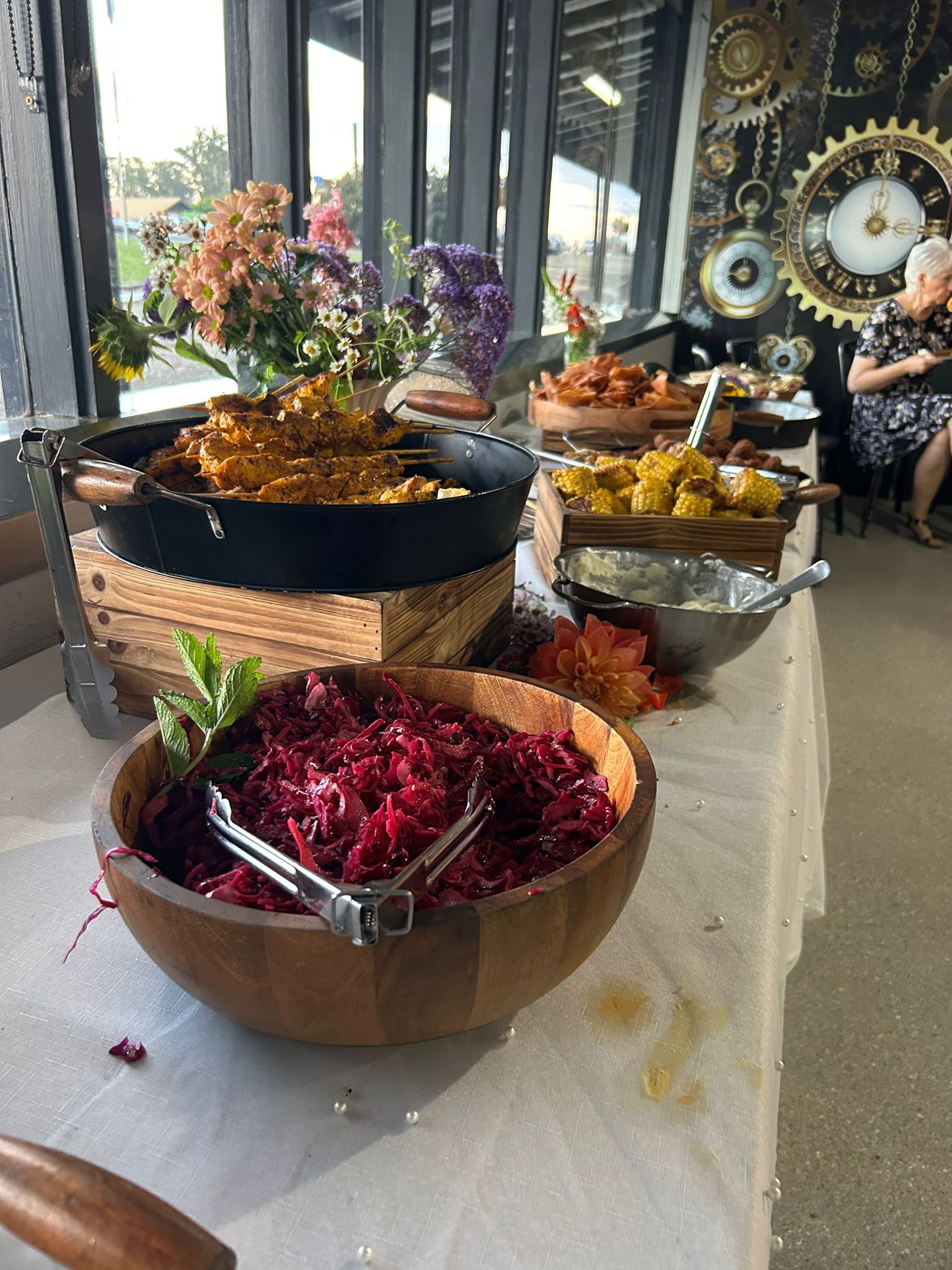 Buffet table with various dishes: beet salad, curry, and other cooked foods. Flowers decorate the background. — The Habibiz Catering In Wingham, NSW