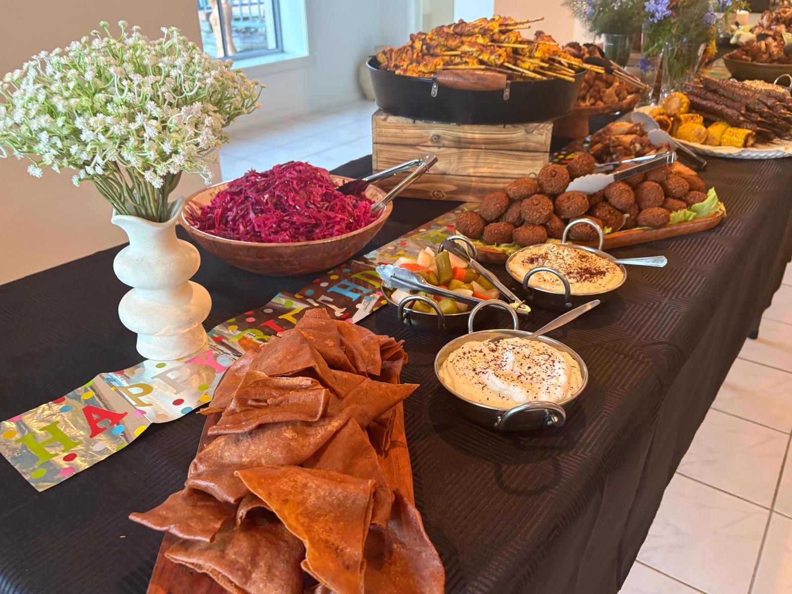 A buffet table with Middle Eastern food, including falafel, hummus, and pita bread. — The Habibiz Catering In Wingham, NSW