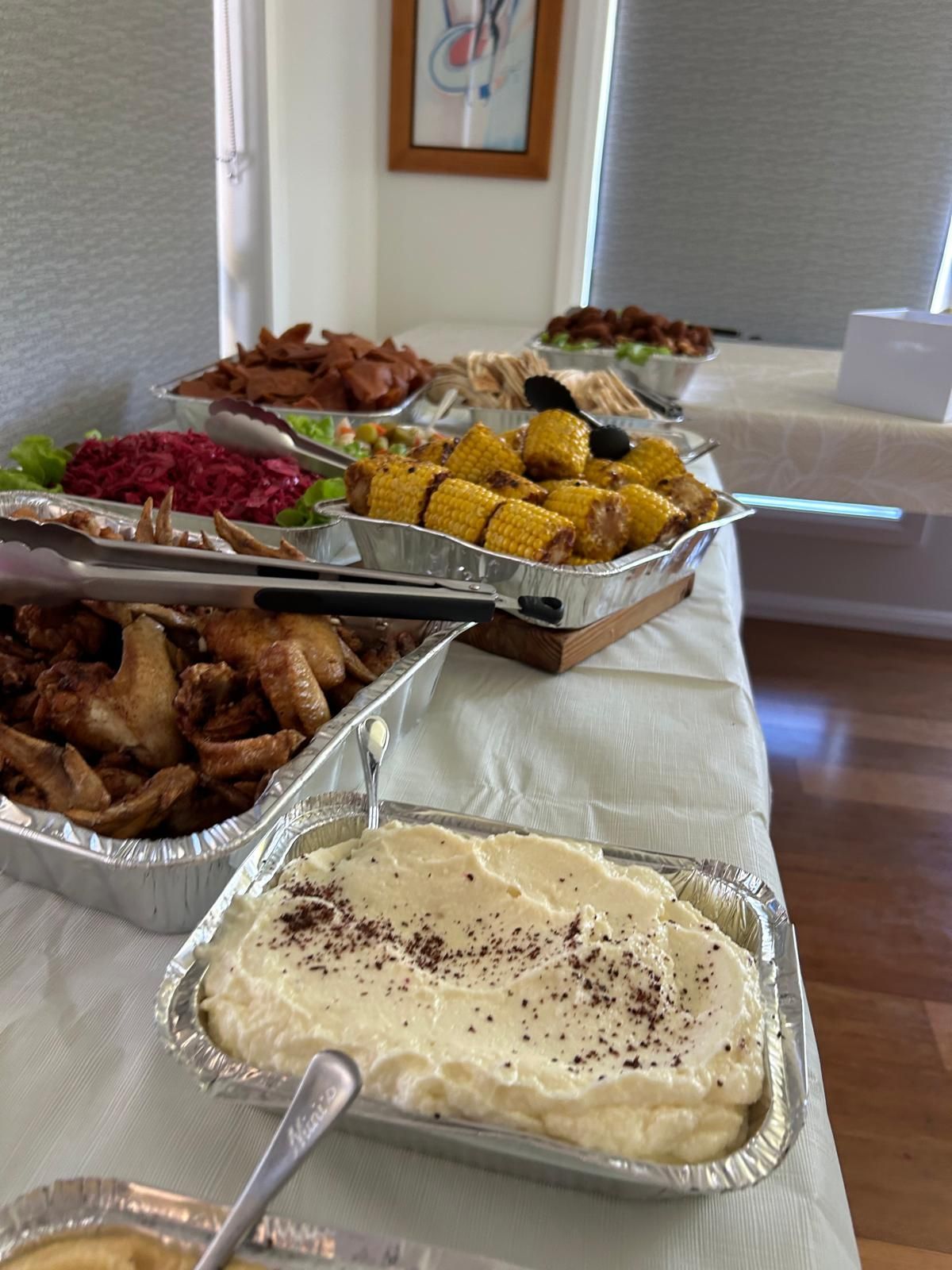 Buffet table with various dishes: fried chicken, corn on the cob, dip, and other sides. — The Habibiz Catering In Wingham, NSW