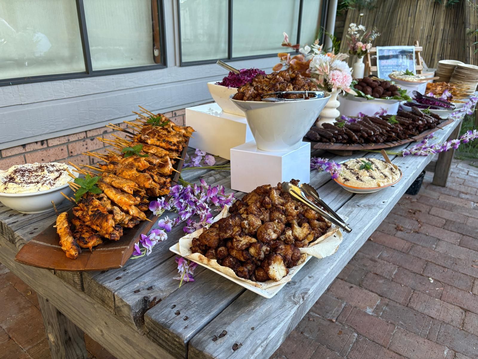 Buffet table with various dishes: fried food, dips, meatballs, flowers. — The Habibiz Catering In Wingham, NSW