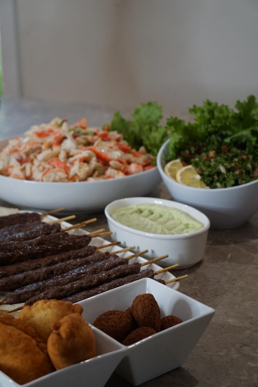 A spread of Middle Eastern food: kebabs, falafel, salad, and a dip, in a bright setting. - The Habibiz Catering in Wingham NSW
