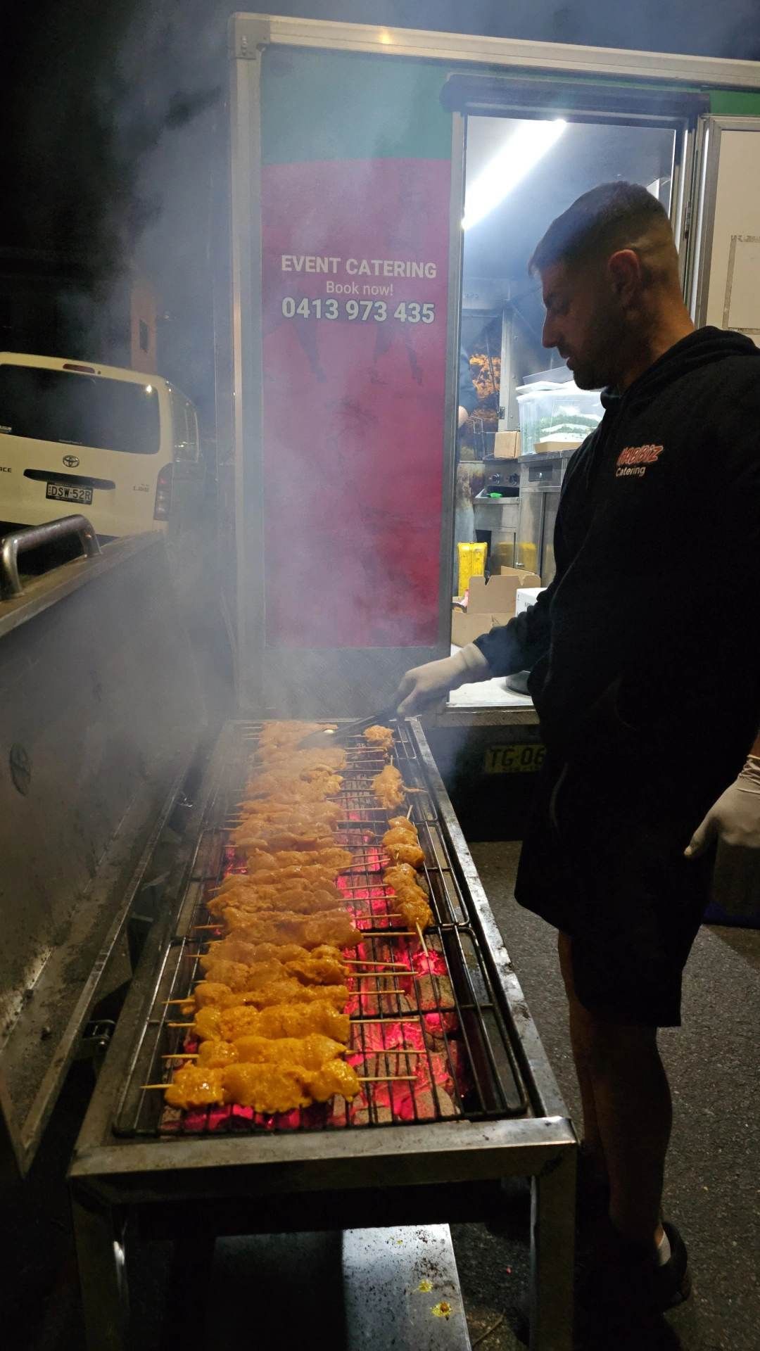 Man Grilling Skewers Over Hot Coals at A Food Truck — The Habibiz Catering In Wingham, NSW