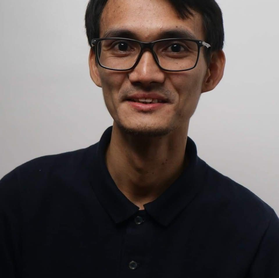 A man wearing glasses and a black shirt looks at the camera