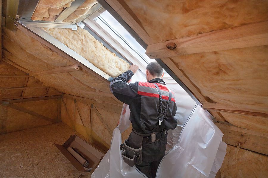 a man is working on a skylight in an attic .