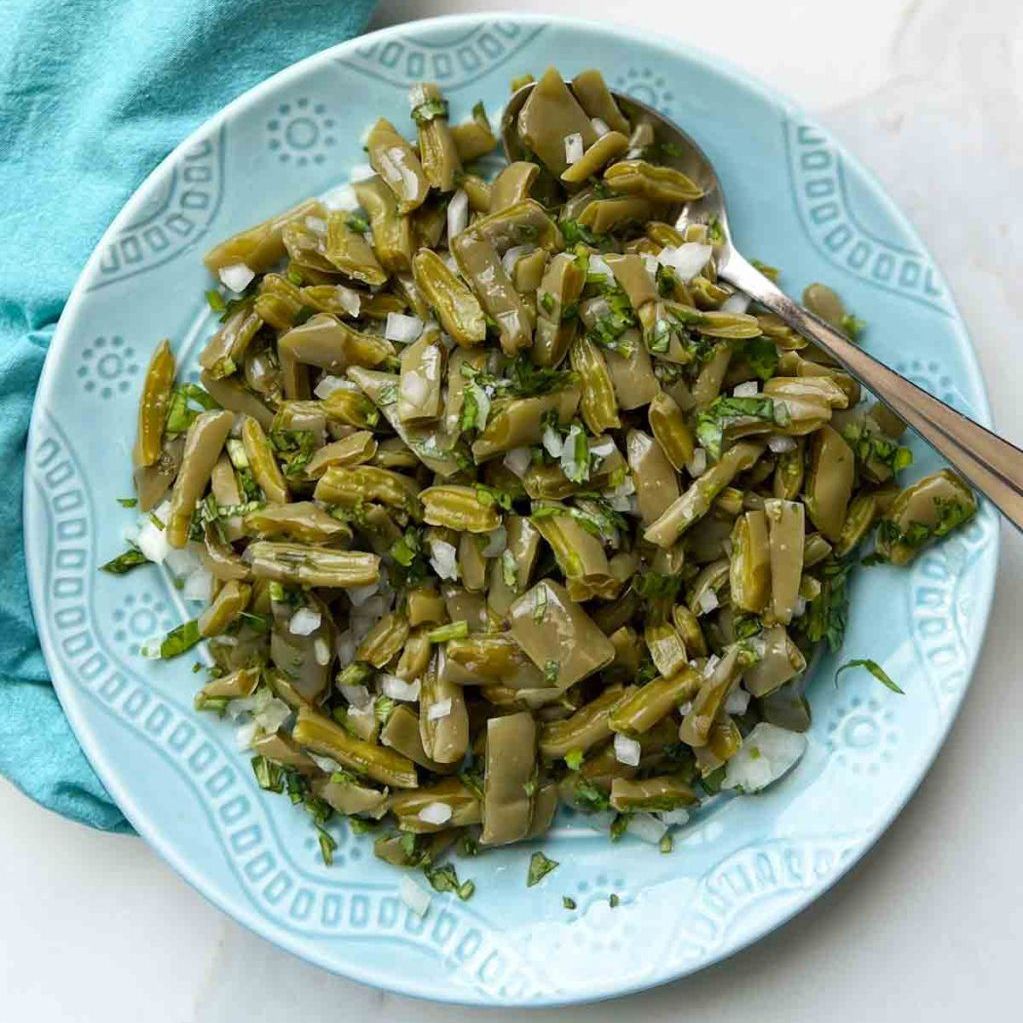 A blue plate topped with green beans and a fork.