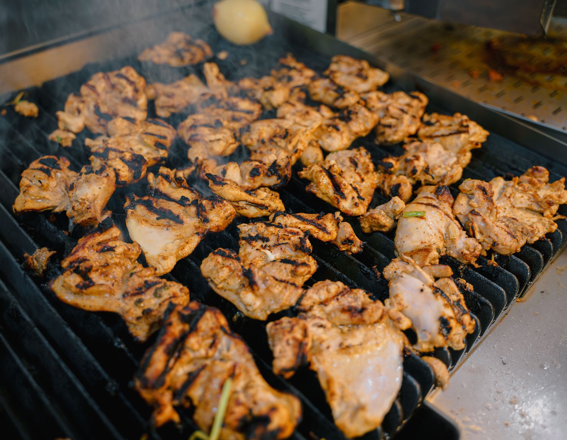 Chicken is being cooked on a grill with smoke coming out of it.