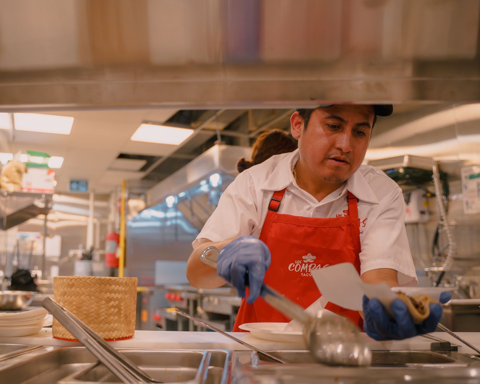 A man in a red apron is preparing food in a kitchen.