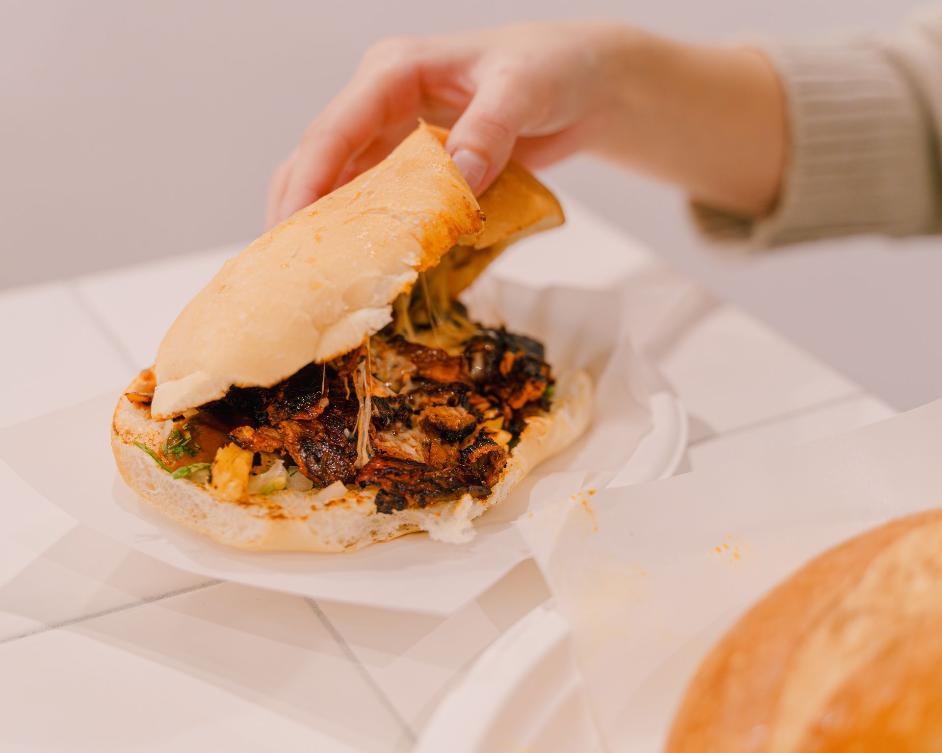 A person is taking a bite out of a sandwich on a table.