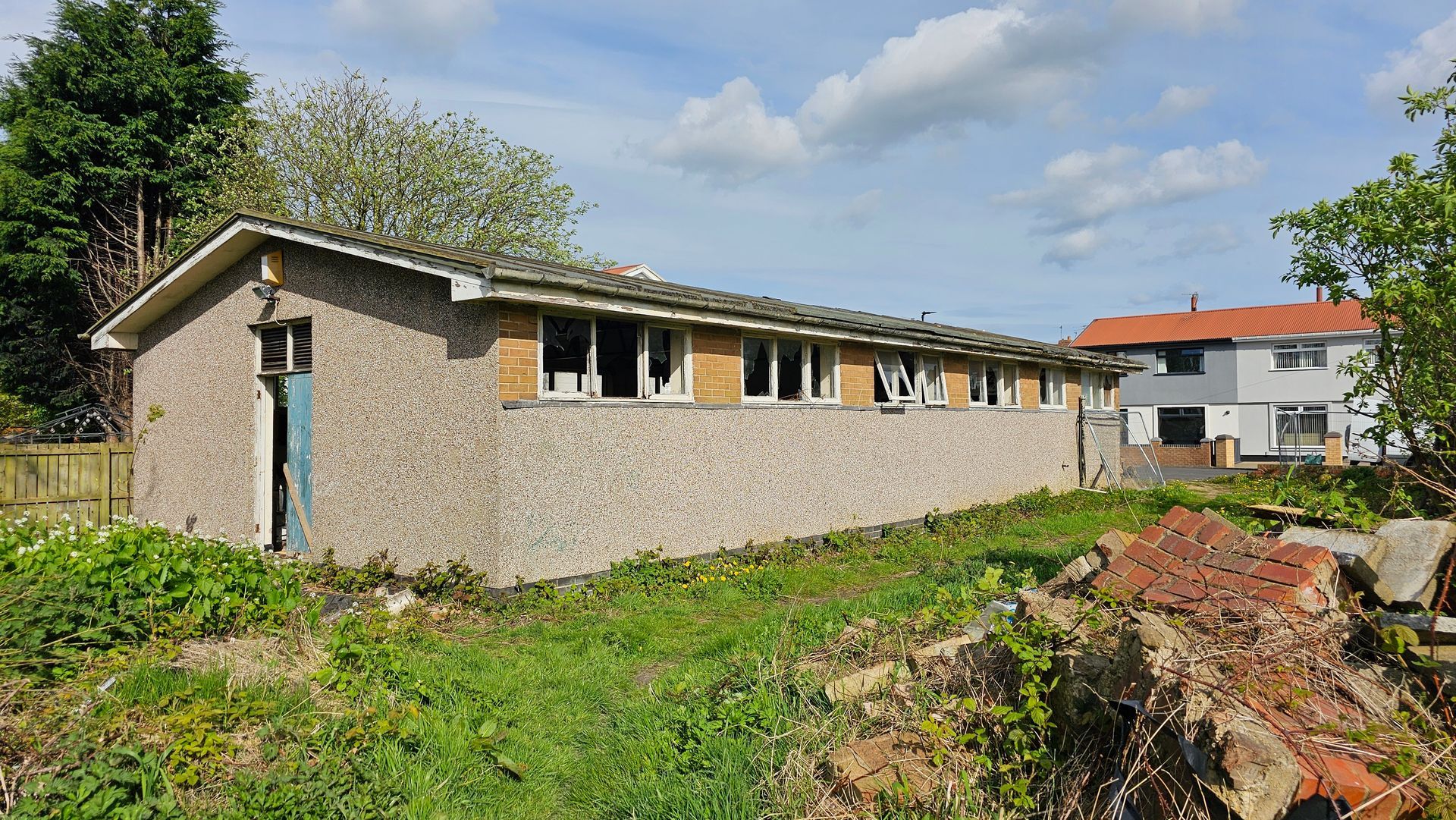 An image of the old, derelict, single storey, concreate prefab building, around 20 meters by 6 meters long, prior to it being demolished.
