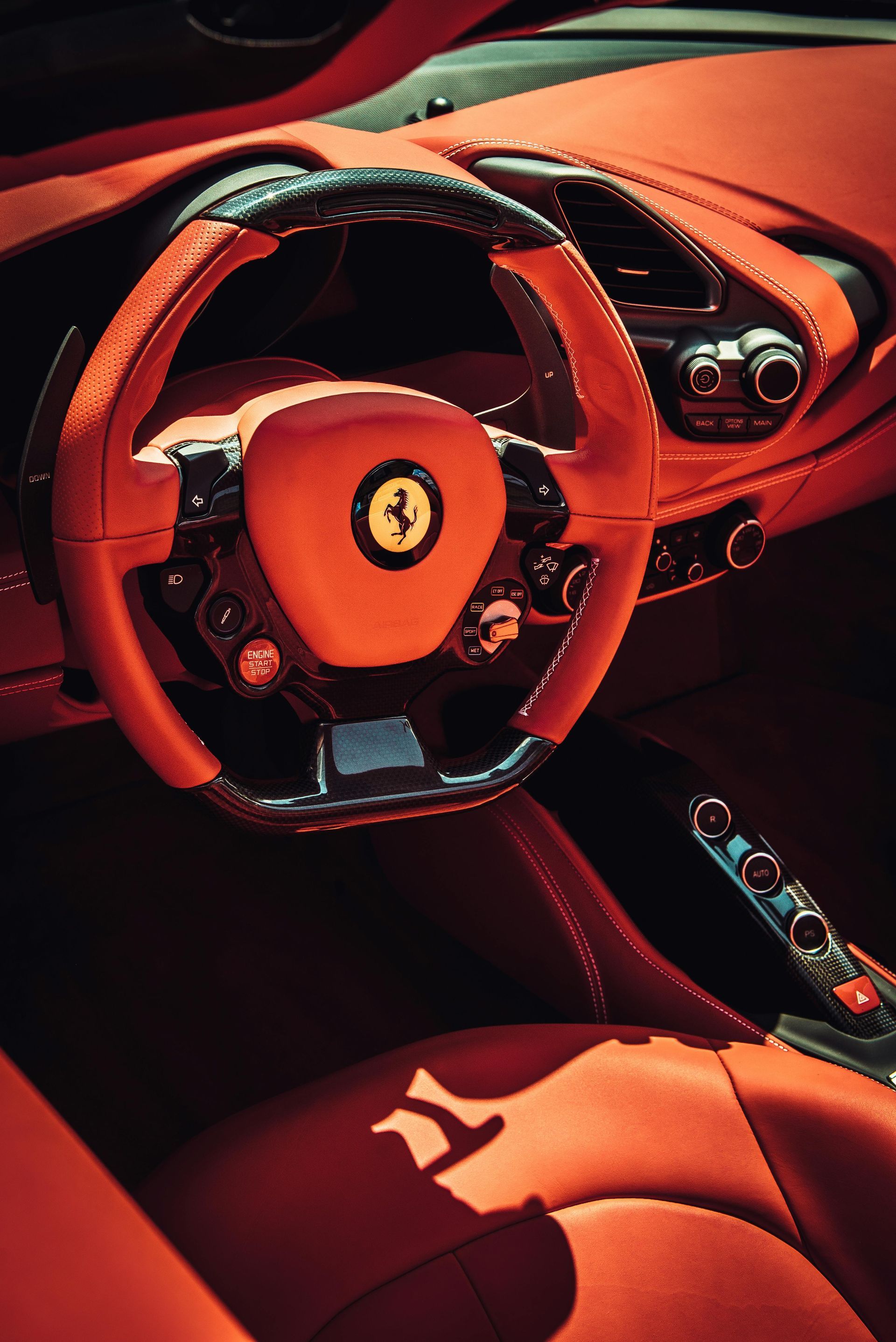 Red Ferrari interior with steering wheel, dashboard, and seats.