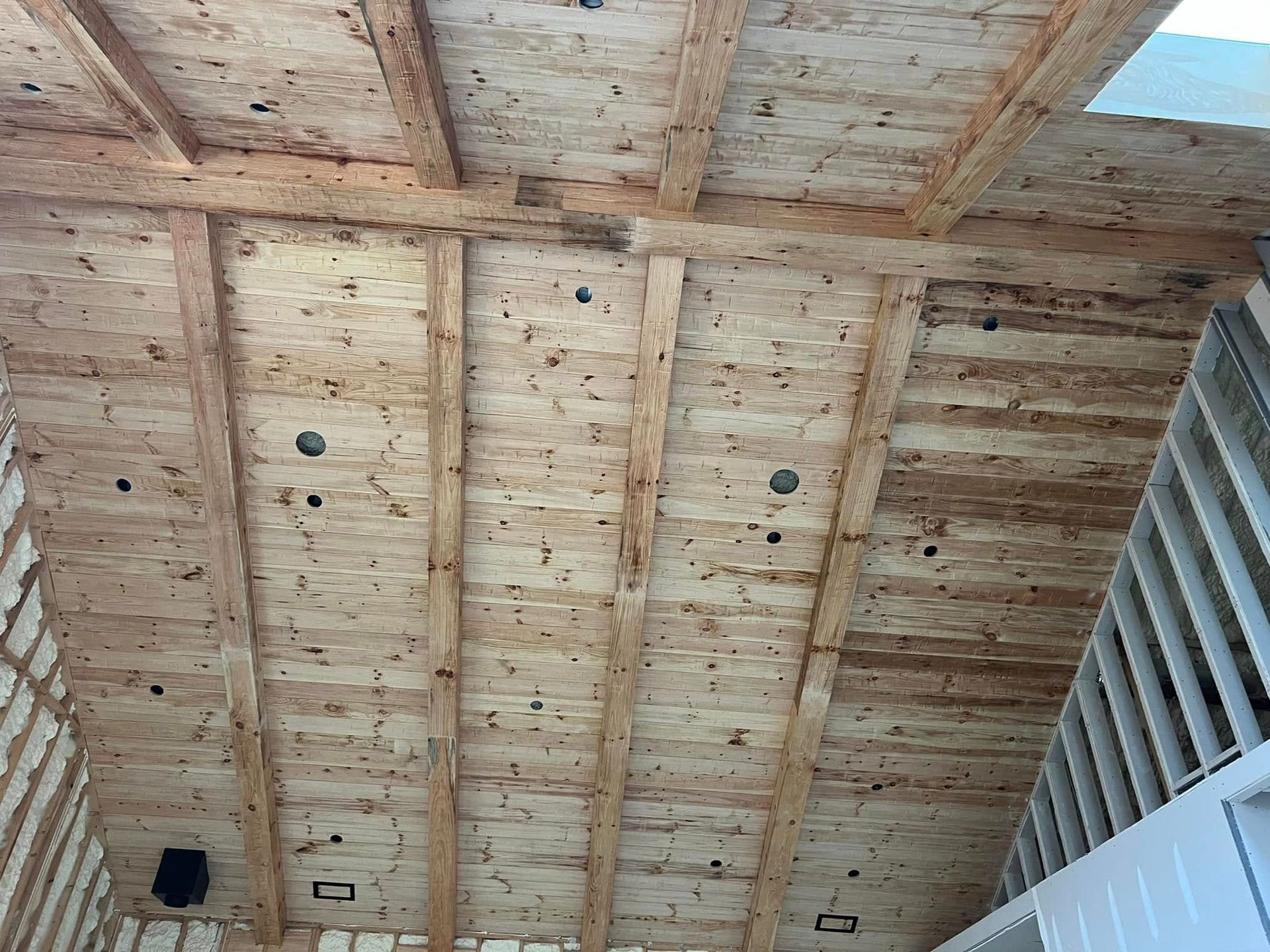 The ceiling of a building is made of wood and has a lot of beams.