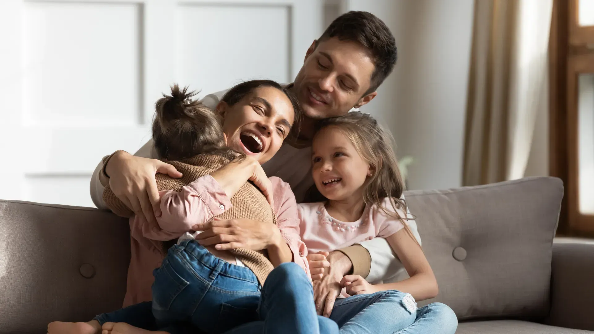 A family is sitting on a couch hugging each other.