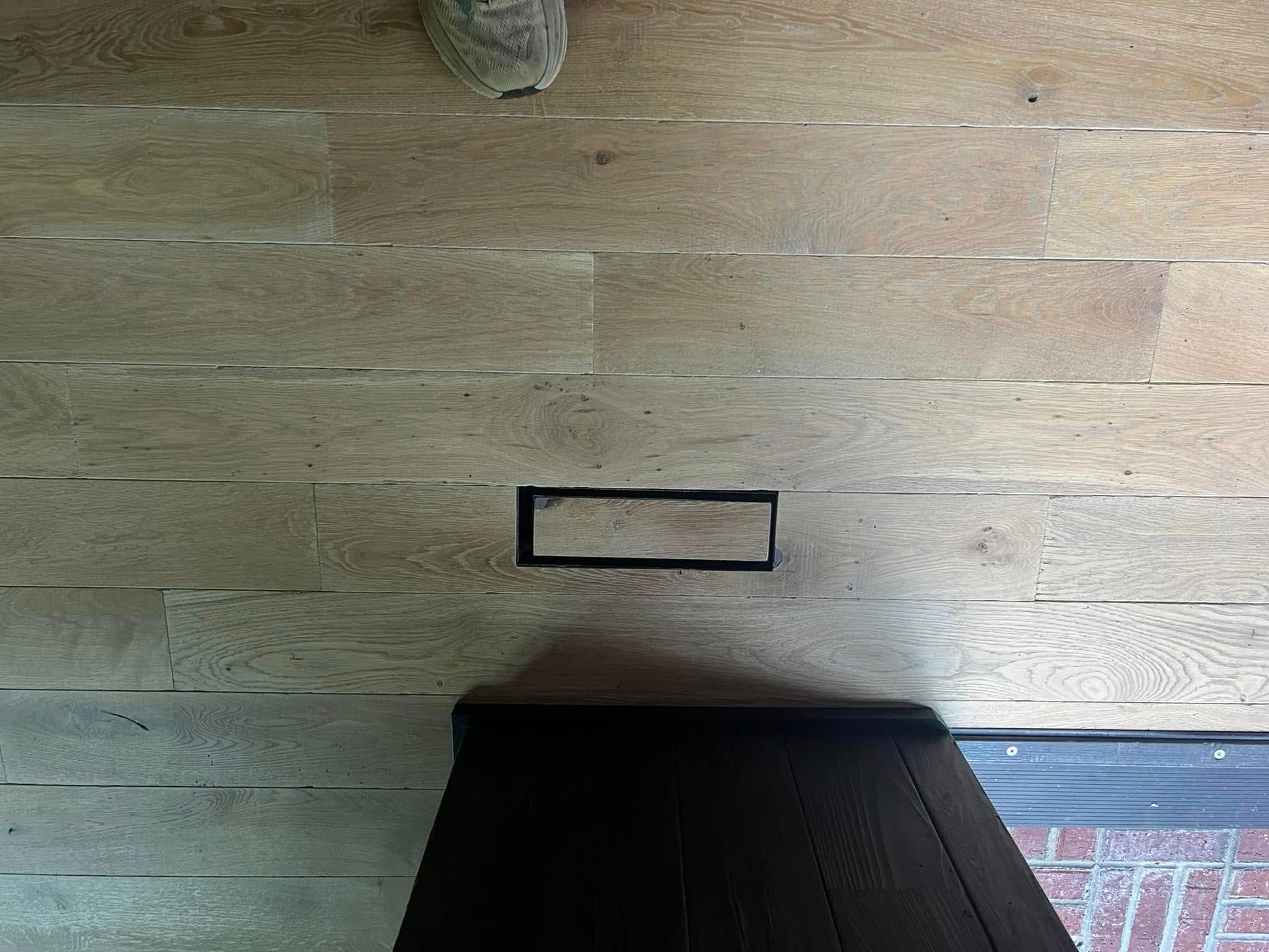 A person is standing on a wooden floor next to a door.