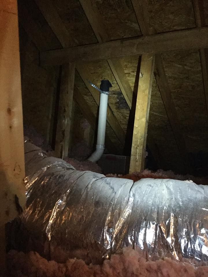 A pipe is hanging from the ceiling of an attic.