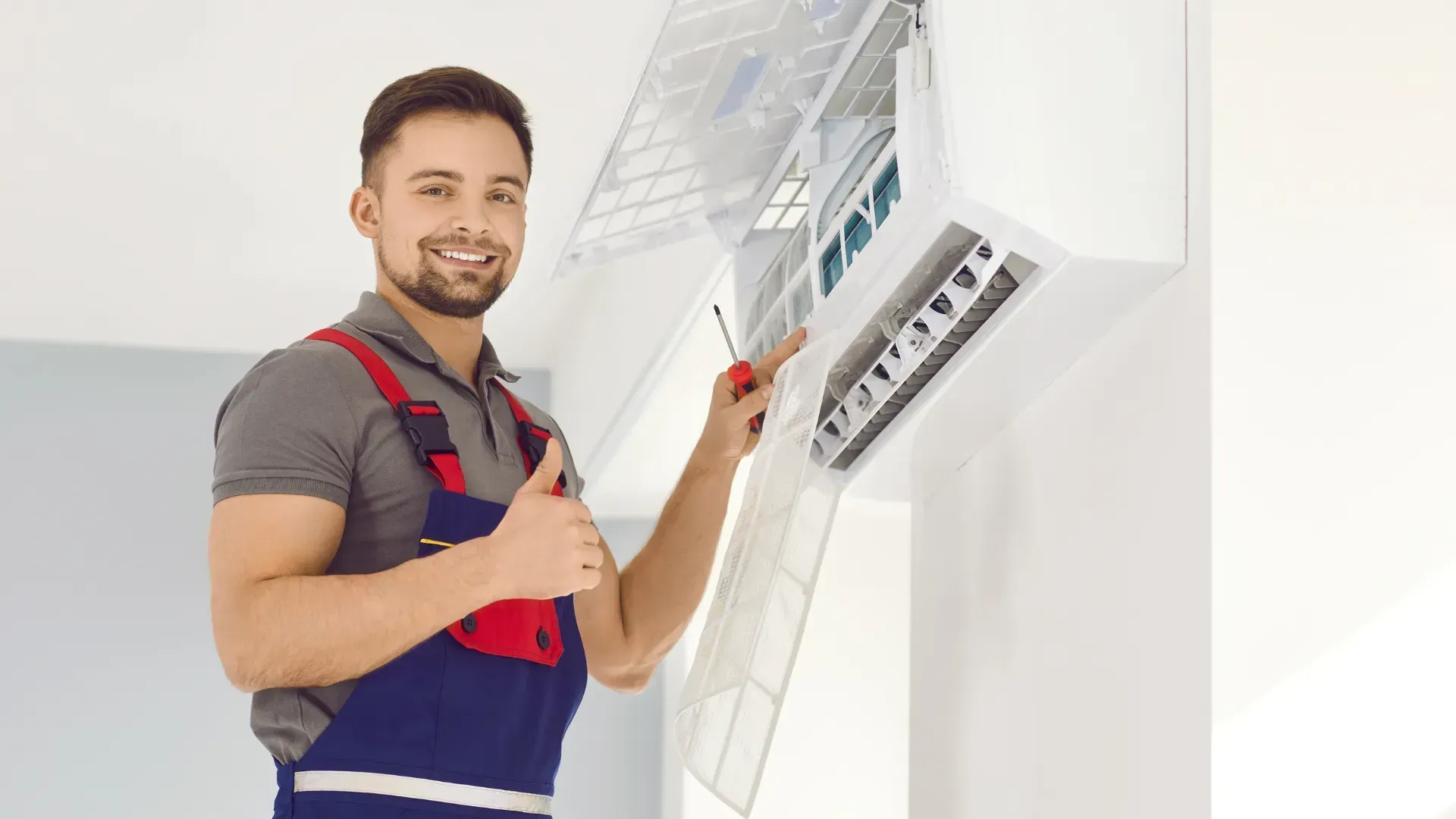 A man is working on an air conditioner and giving a thumbs up.
