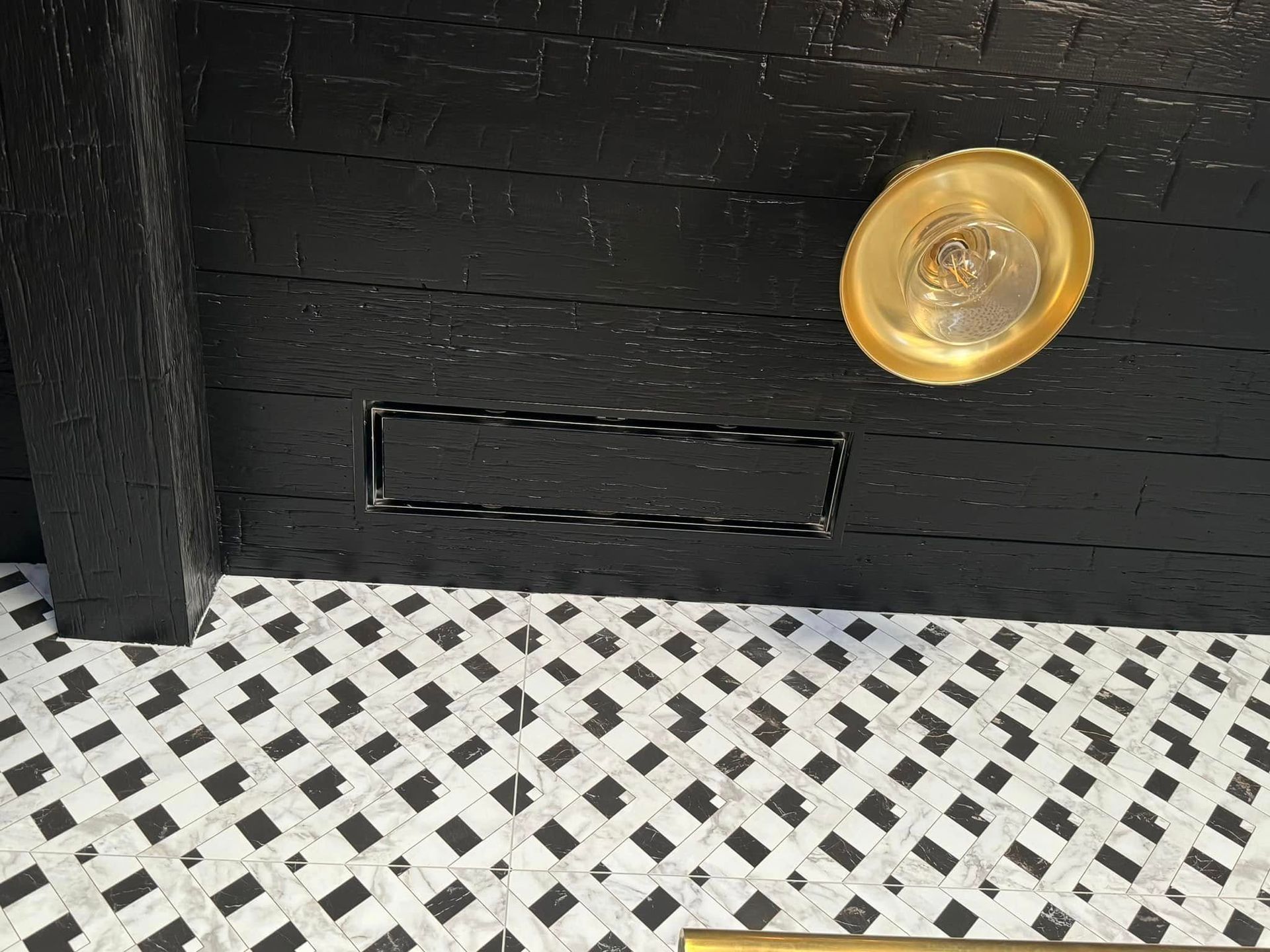 A black and white tile floor with a gold plate on the wall.