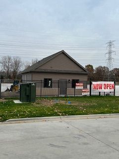 A building with a fence around it and a sign that says `` now open ''.