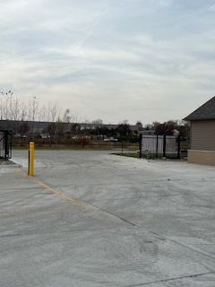 A large concrete parking lot with a house in the background.