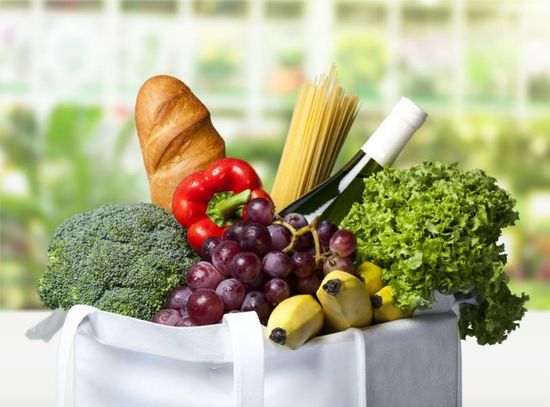 una borsa della spesa con delle verdure, pasta e vino