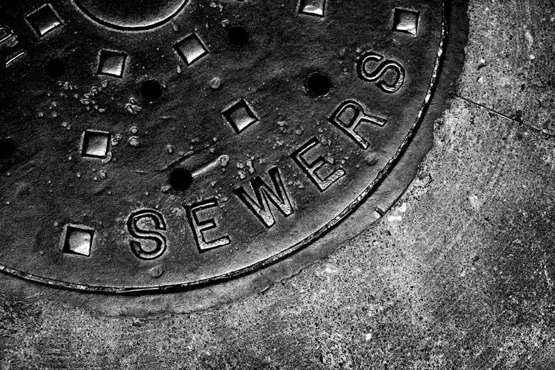 A black and white photo of a manhole cover that says sewer on it.