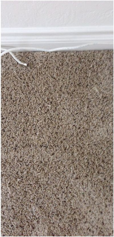 A close up of a brown carpet with a white trim.