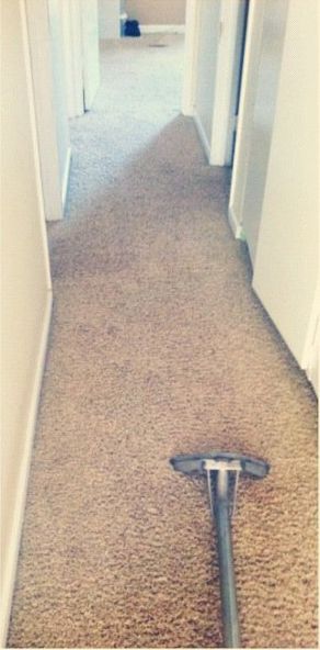 A vacuum cleaner is sitting on a carpet in a hallway.