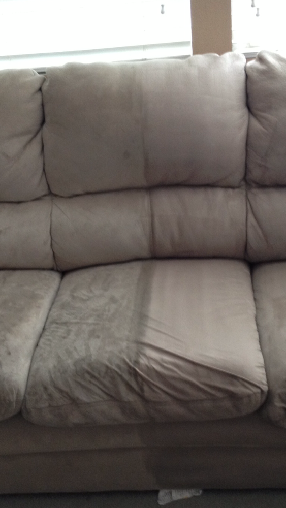 A couch is sitting in a living room next to a window.