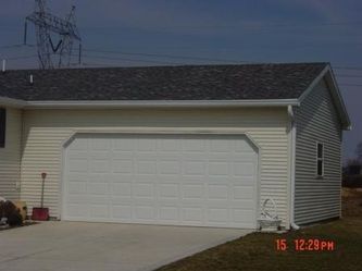 White garage with gray roof and siding, on a sunny day.