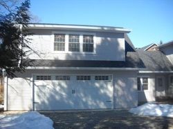 Two-story gray house with a garage door. Windows on the second floor, snow on the ground.