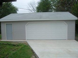 Gray garage with white garage door and side door on a concrete driveway.