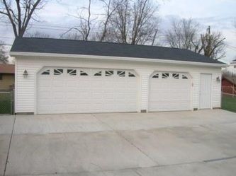 White garage with two doors and a small side door on a concrete driveway.
