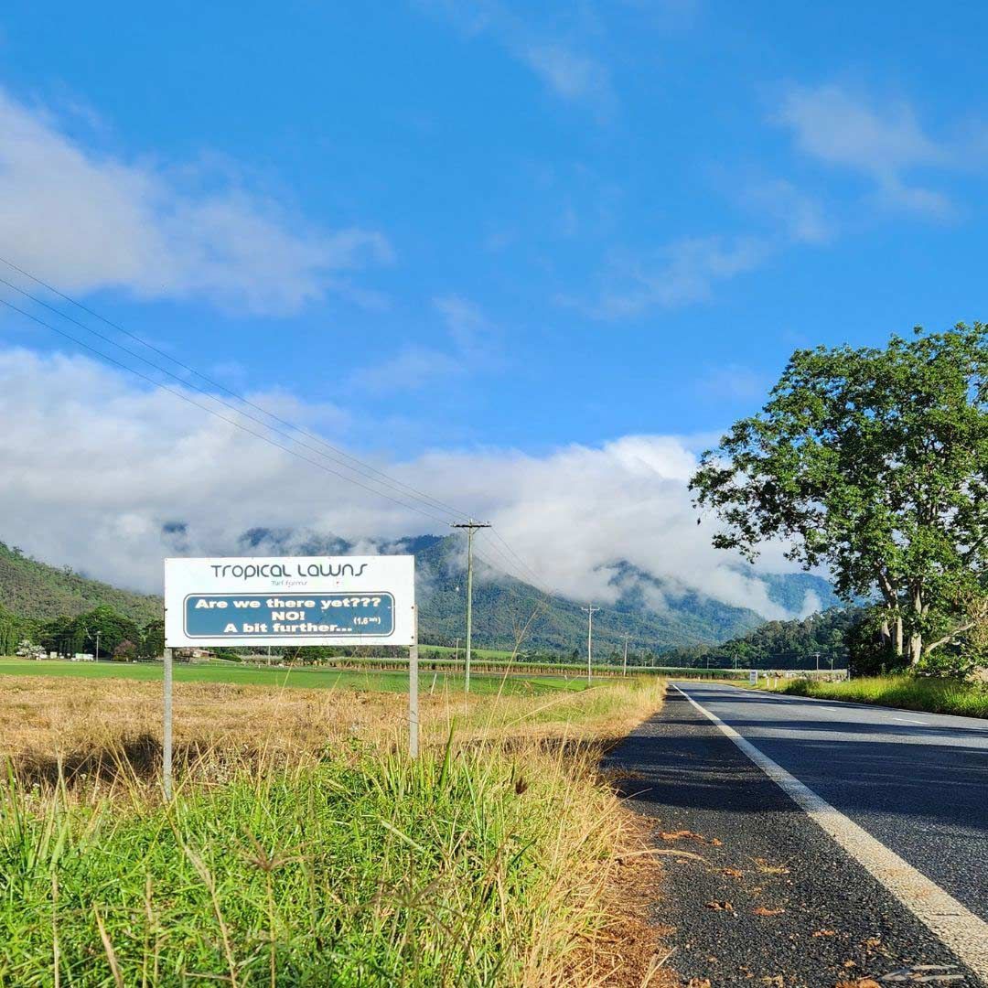 A Road With A Sign On The Side Of It And Mountains In The Background — Tropical Lawns Pty Ltd In Little Mulgrave Qld