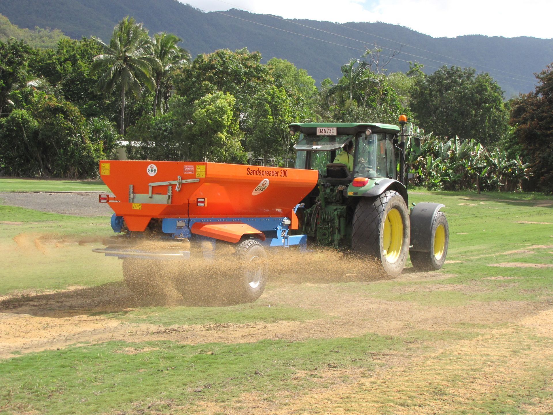 A tractor is spreading fertilizer on a lush green field