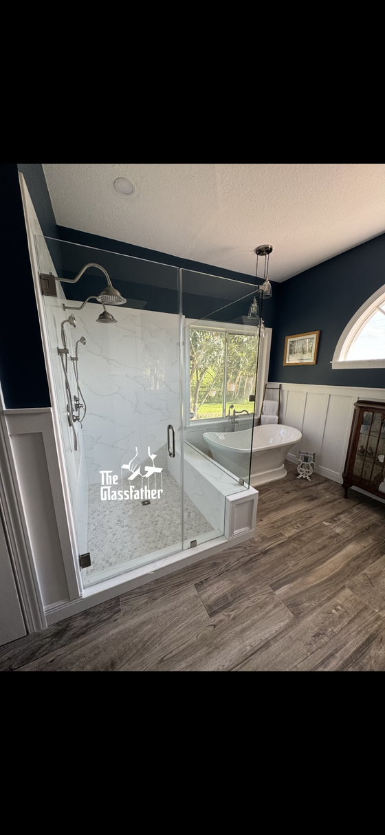 A bathroom with a walk in shower , tub , sink and window.