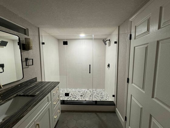 A bathroom with a walk in shower and a sink.