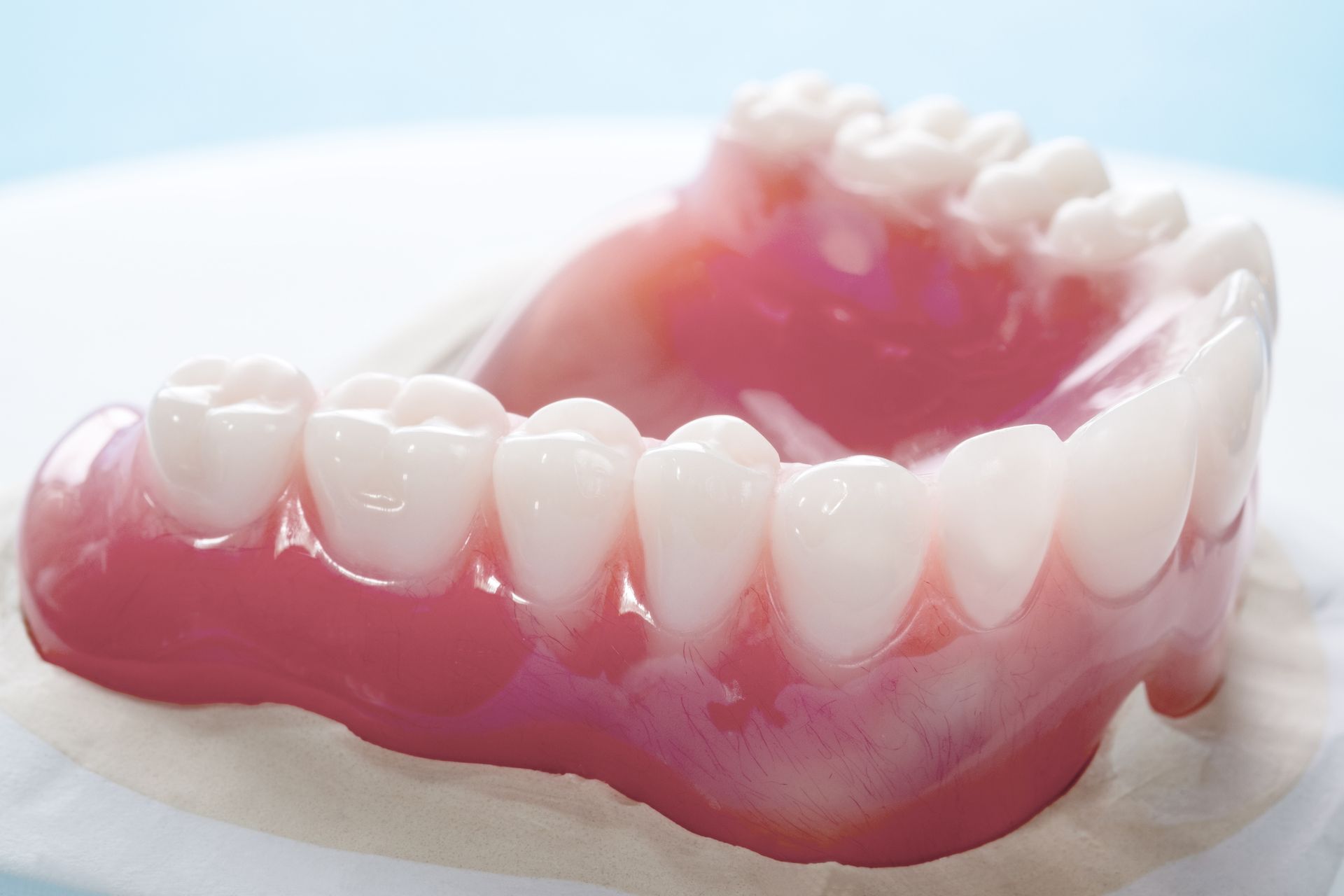 Dentures, set of artificial teeth, with pink gums and white teeth on a blue background.