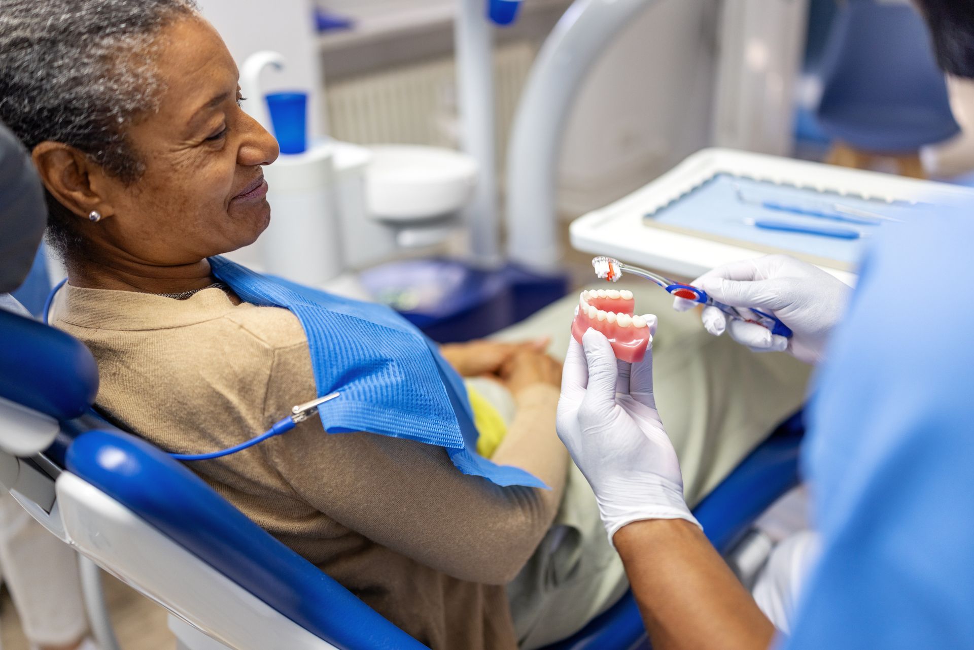 Dentist showing dentures to a patient in a dental chair.