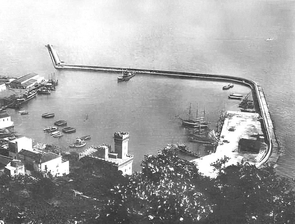 Una donna con le cuffie sorride alla telecamera, seduta a una scrivania. Si trova in un ufficio con una mappa del mondo e un globo sullo sfondo.