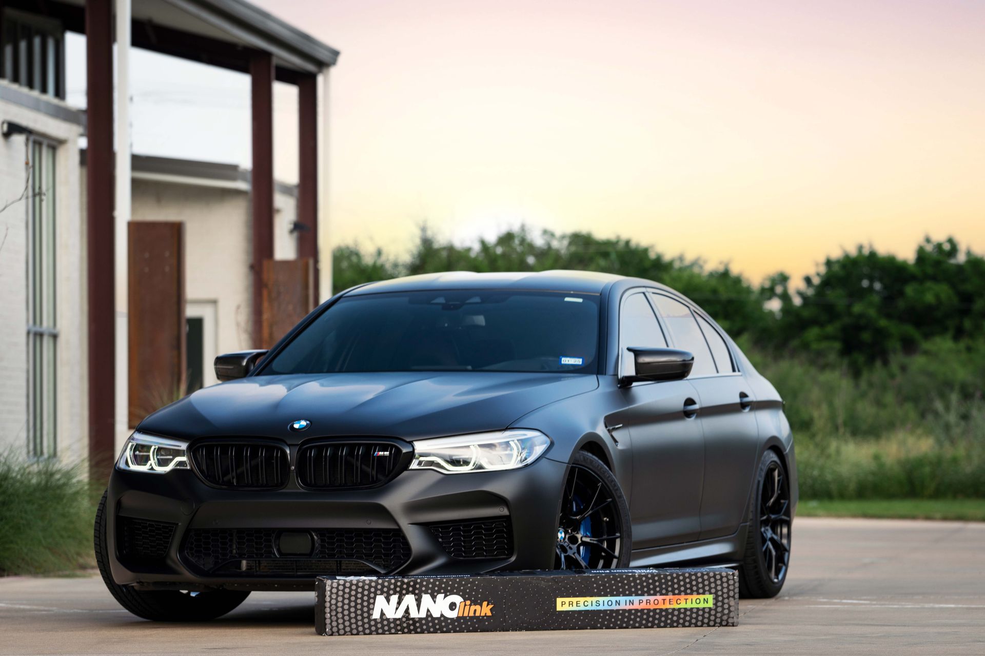 A black bmw m5 is parked in front of a house.