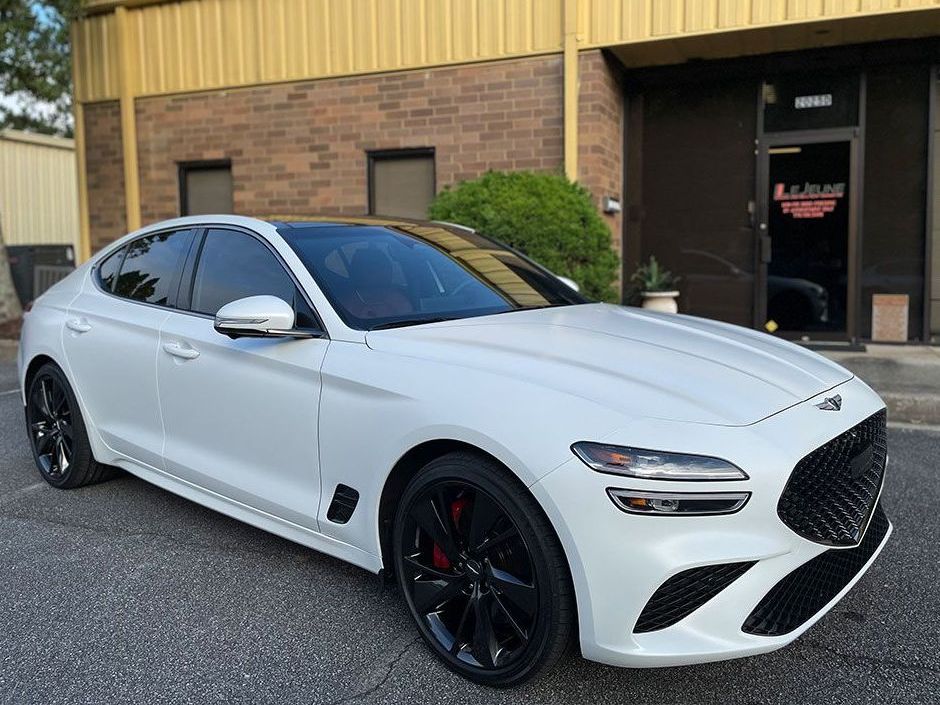A white car is parked in front of a brick building.