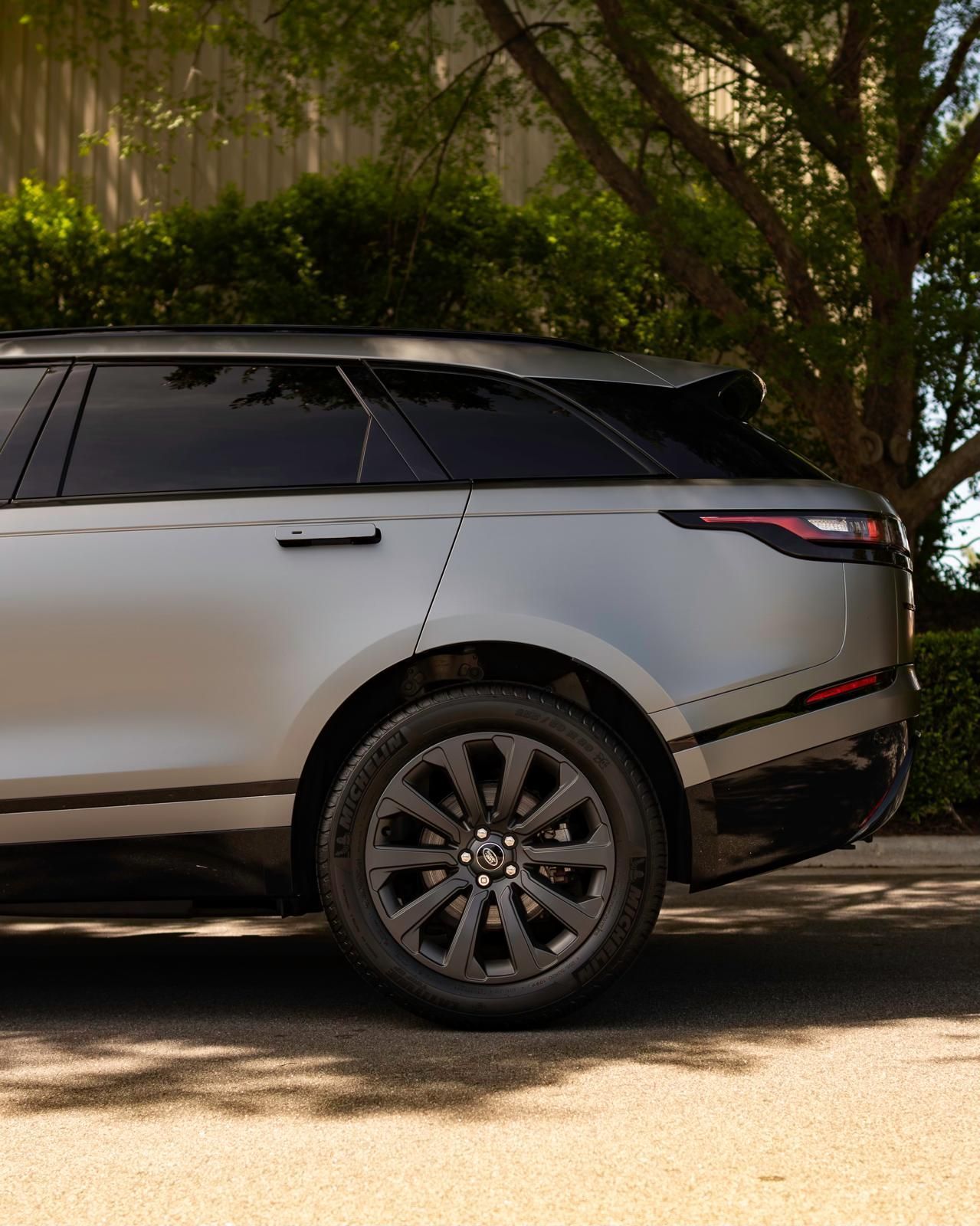 A silver range rover velar is parked on the side of the road.