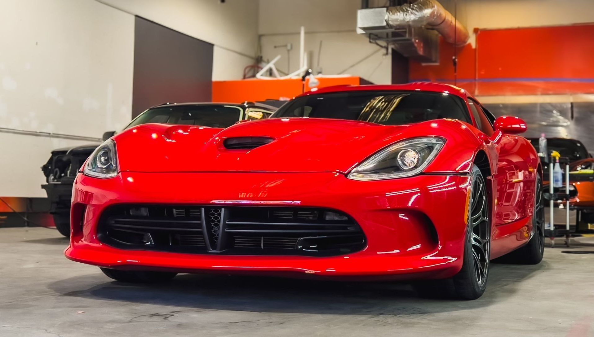 A red dodge viper is parked in a garage