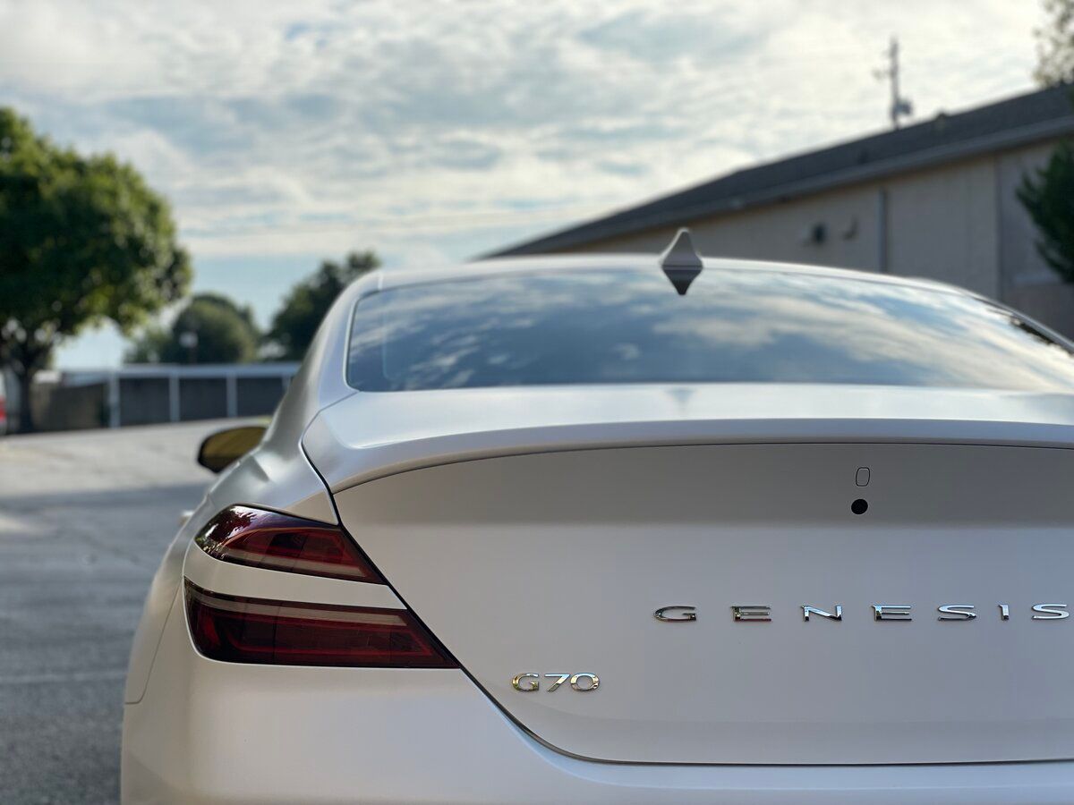 a white genesis car is parked in front of a building