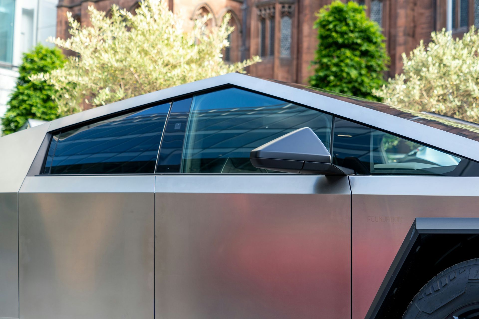 A close up of a tesla cybertruck parked in front of a building.