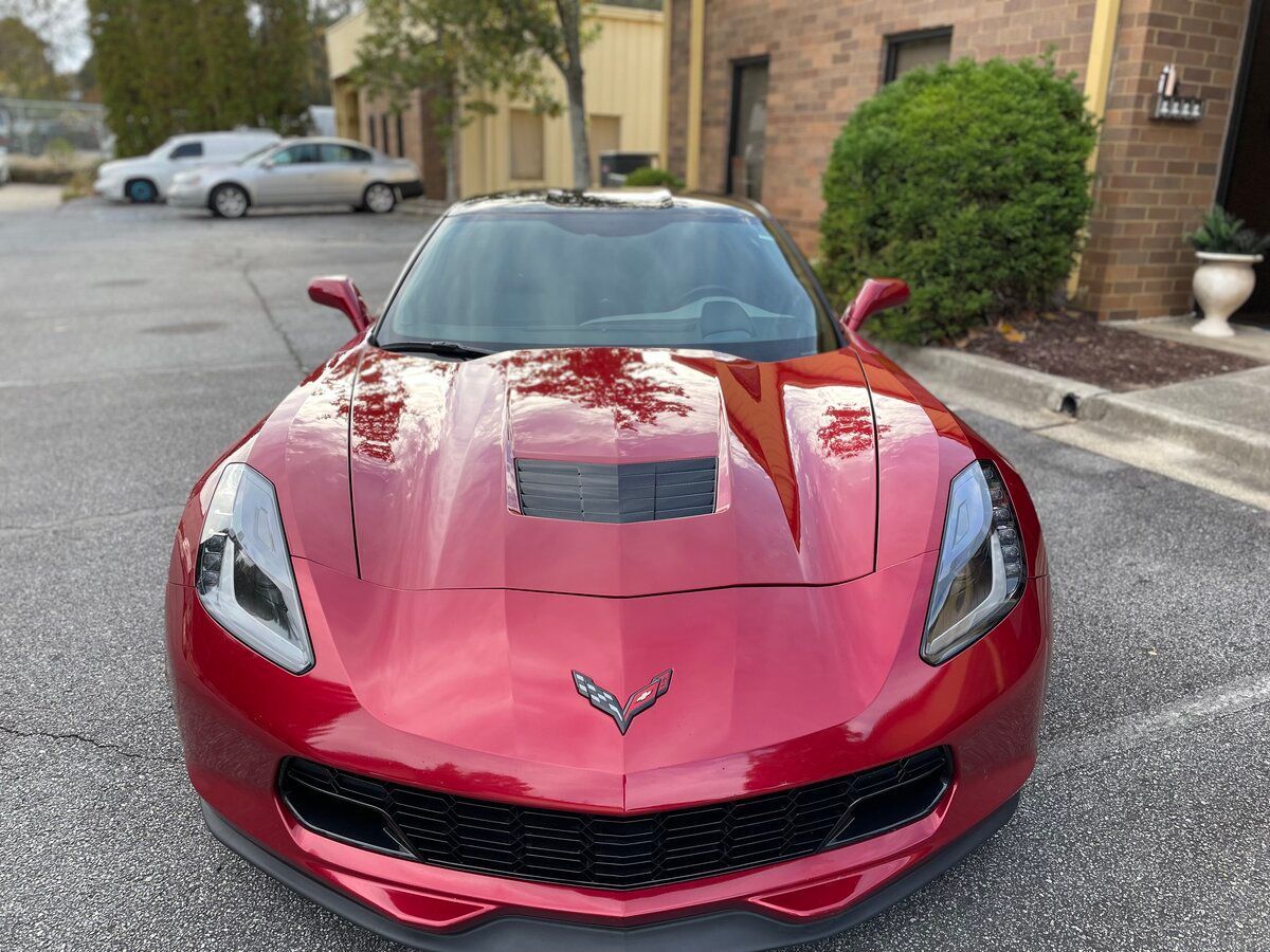 a red corvette is parked in a parking lot in front of a building .